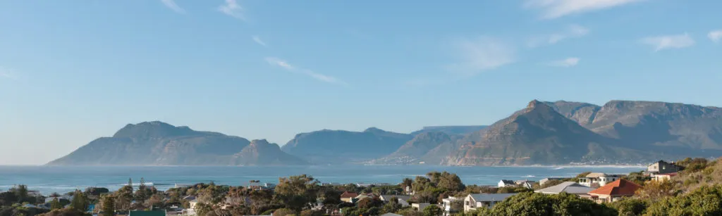 Coastal town with mountains in the background under a clear blue sky