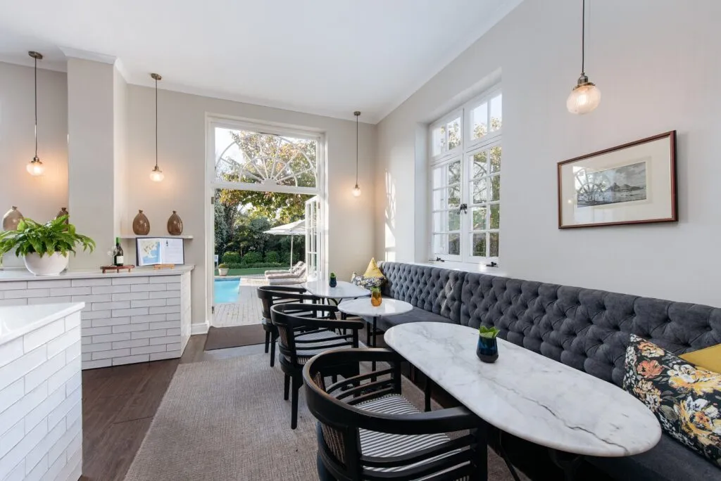 Modern dining area with black chairs white tables and a view of a pool