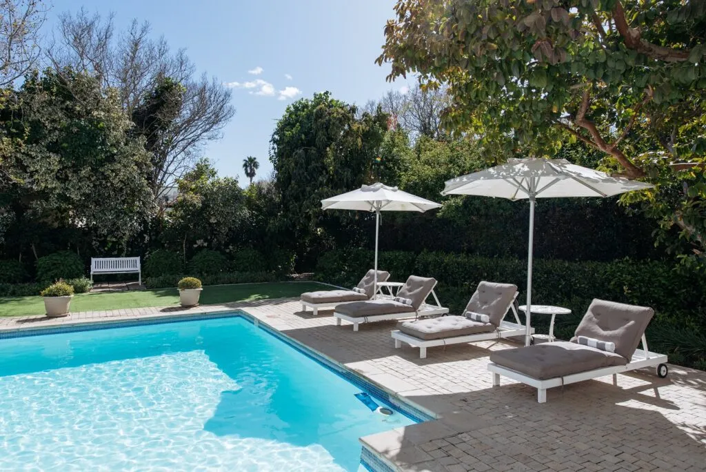 Swimming pool with lounge chairs and umbrellas in a garden setting