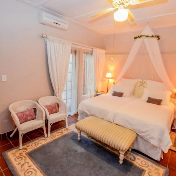Bedroom with two beds canopy ceiling fan and seating area on tiled floor