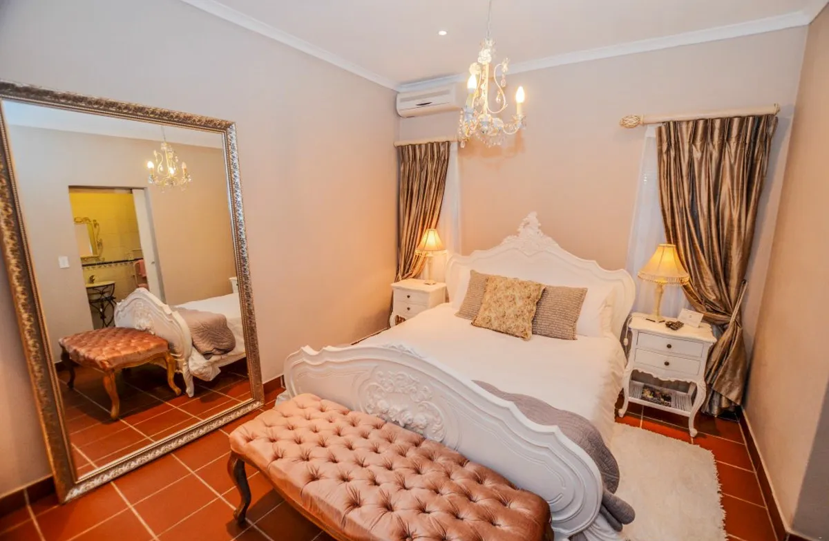 Elegant bedroom with white ornate bed pink bench and large mirror