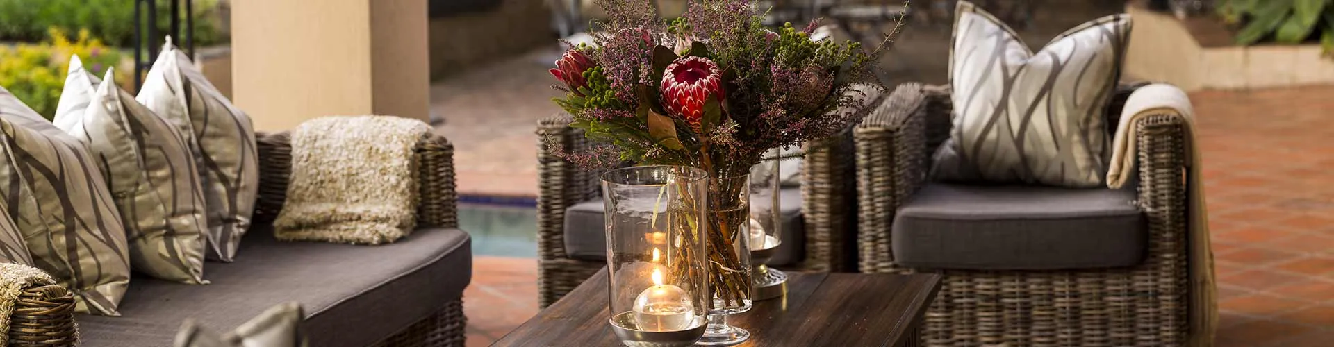 Outdoor seating area with a wooden table candles and a vase of flowers