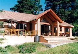 Singlestory house with wooden deck and garden surrounded by trees