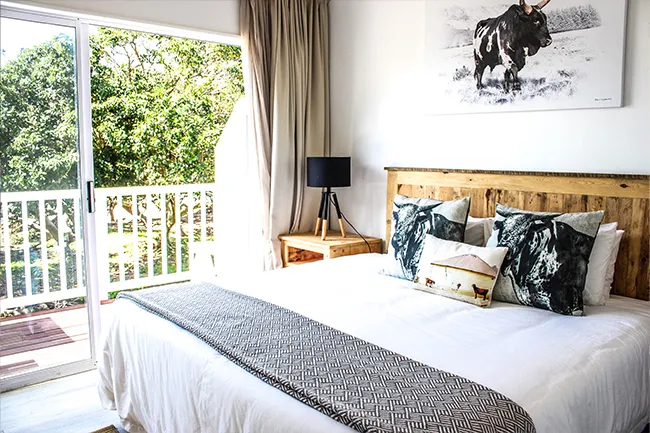 Bedroom with large bed patterned throw and balcony overlooking greenery