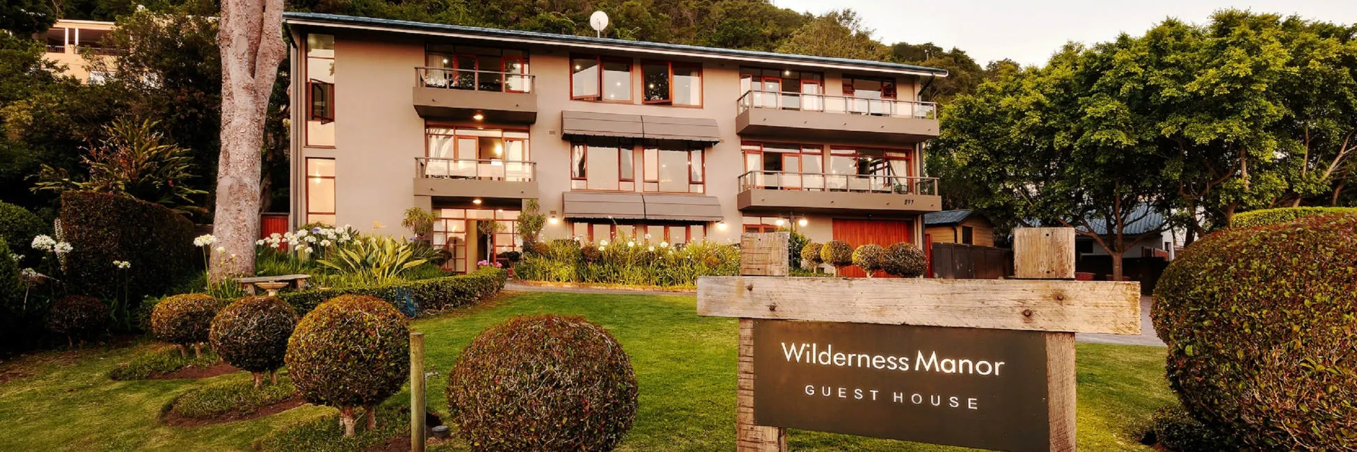 Wilderness Manor Guest House with wellmaintained garden and trees in the background