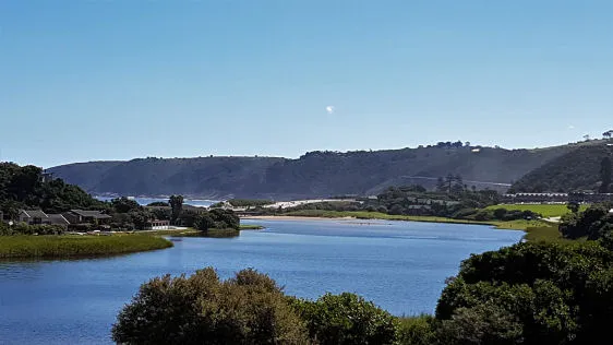 A river flowing through green hills under a clear blue sky