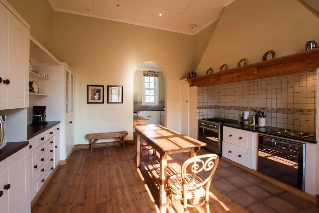 Sunlit kitchen with wooden table white cabinets and tiled floor
