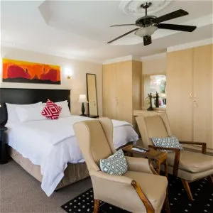 Modern bedroom with two armchairs bed and ceiling fan