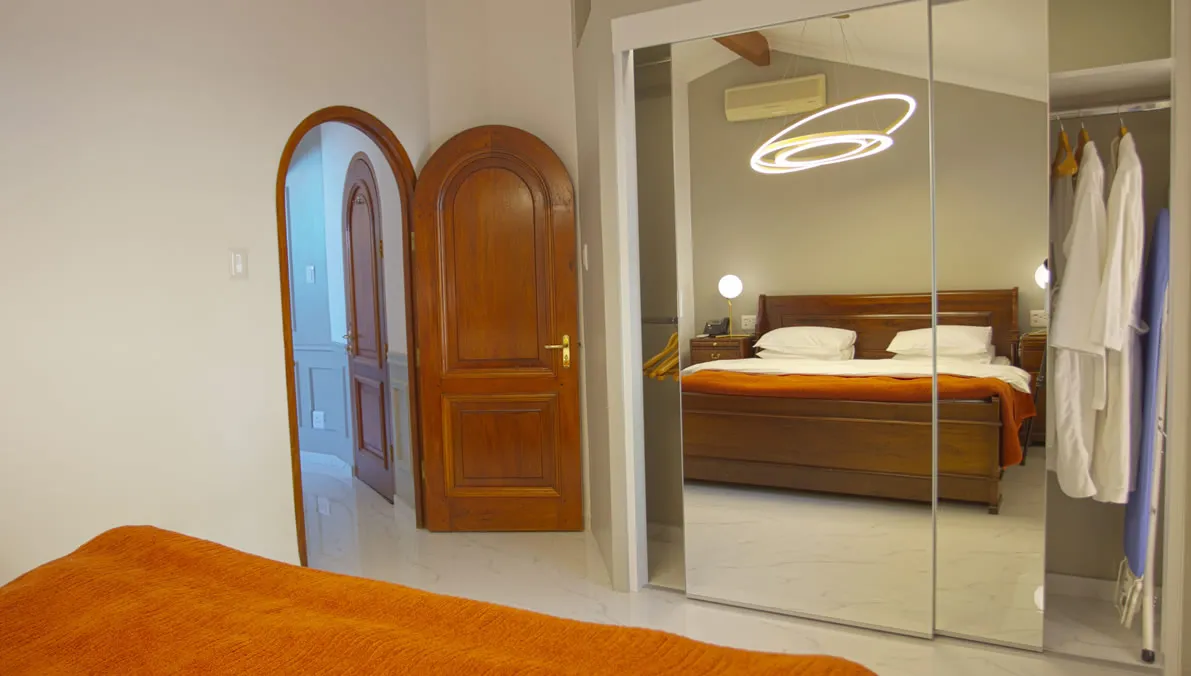 Bedroom with wooden doors mirrored closet and orange bedspread