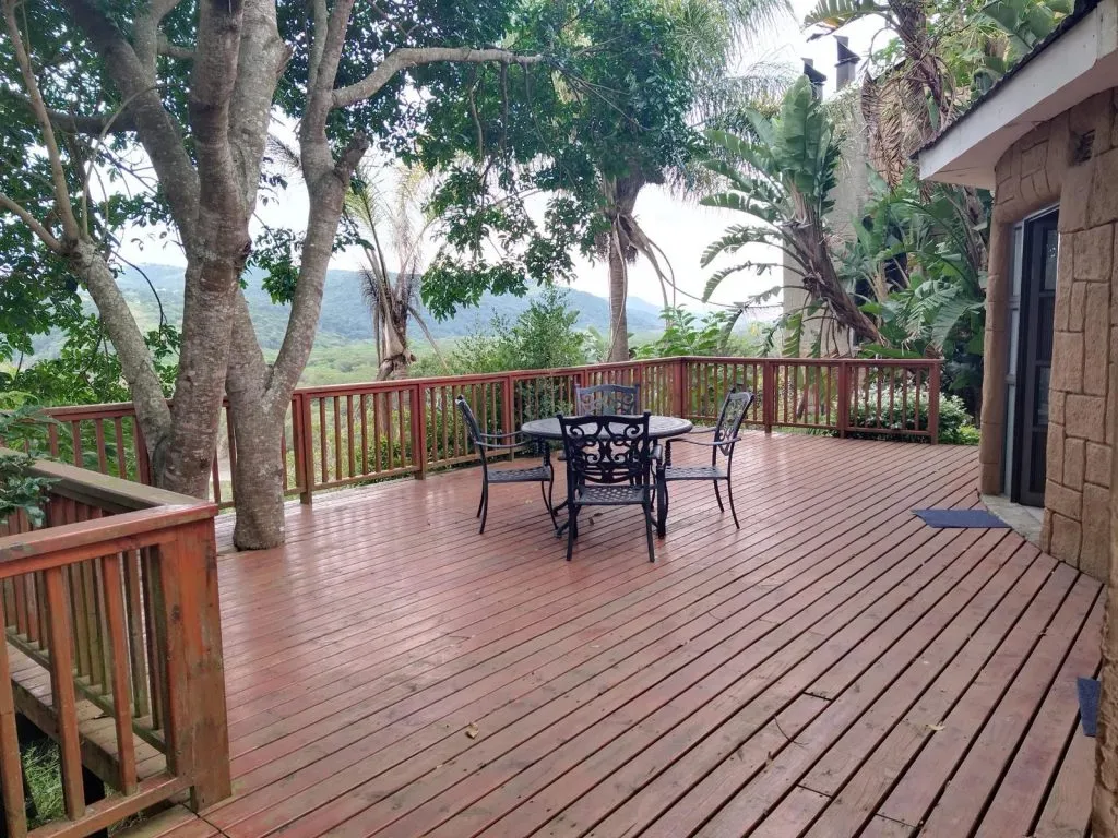 Wooden deck with table and chairs surrounded by trees and greenery