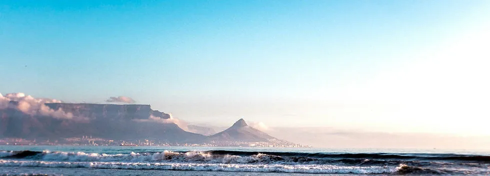 Ocean waves with mountains in the background under a clear sky