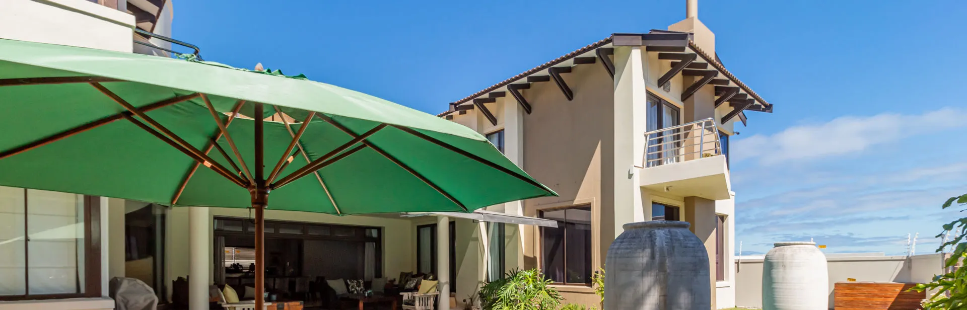 Modern house with a patio green umbrella and water tanks in the background