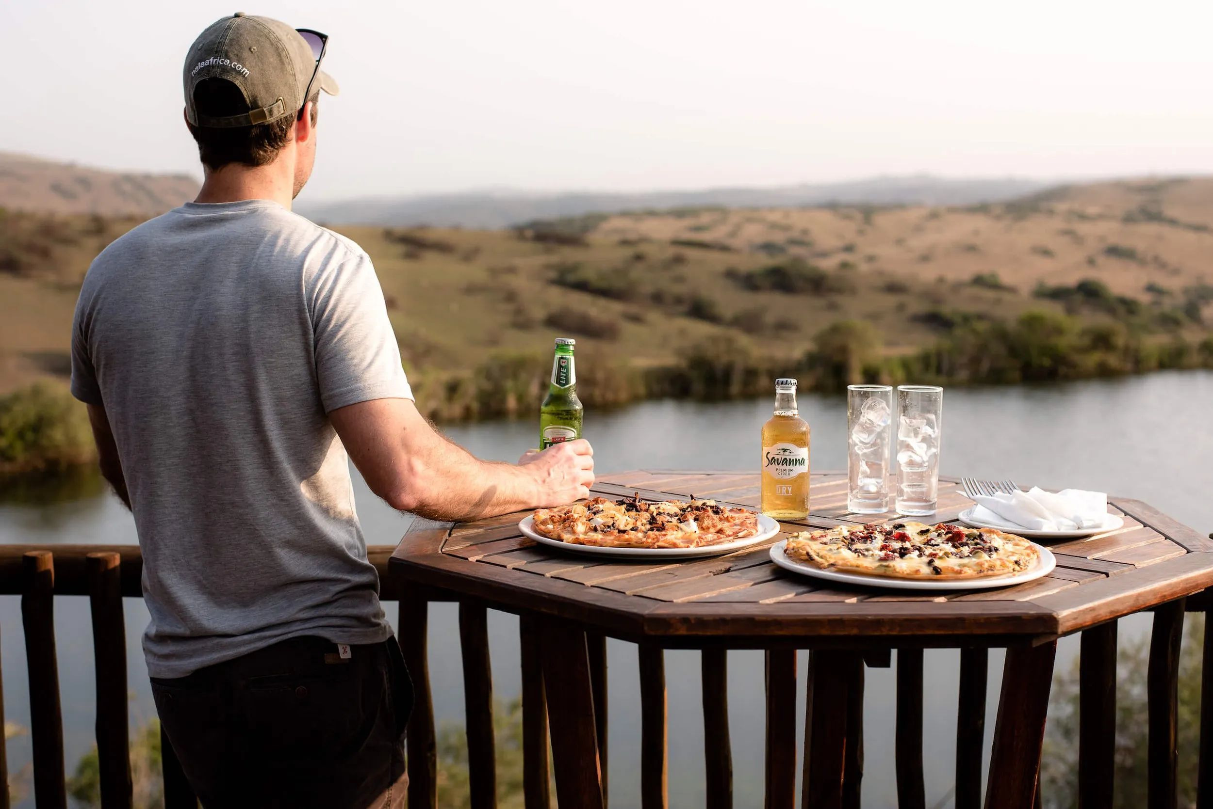 Man holding beer pizzas on table scenic view of lake and hills