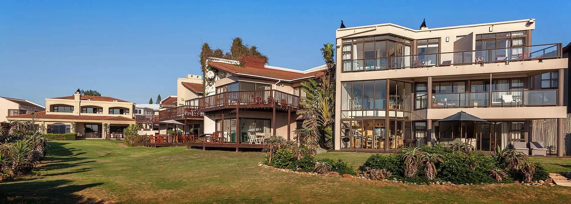 Modern houses with large windows and wooden decks in a landscaped garden