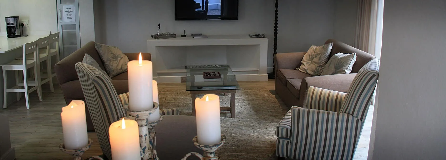 Living room with lit candles sofas and a TV on the wall