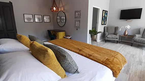 Modern bedroom with large bed mustard throw and wallmounted TV