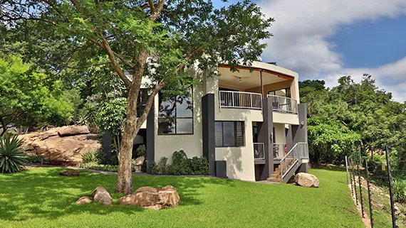 Modern twostory house with large windows surrounded by greenery and rocks