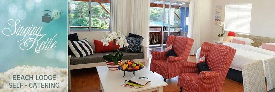 Cozy living room with red armchairs white sofa and beach lodge advertisement