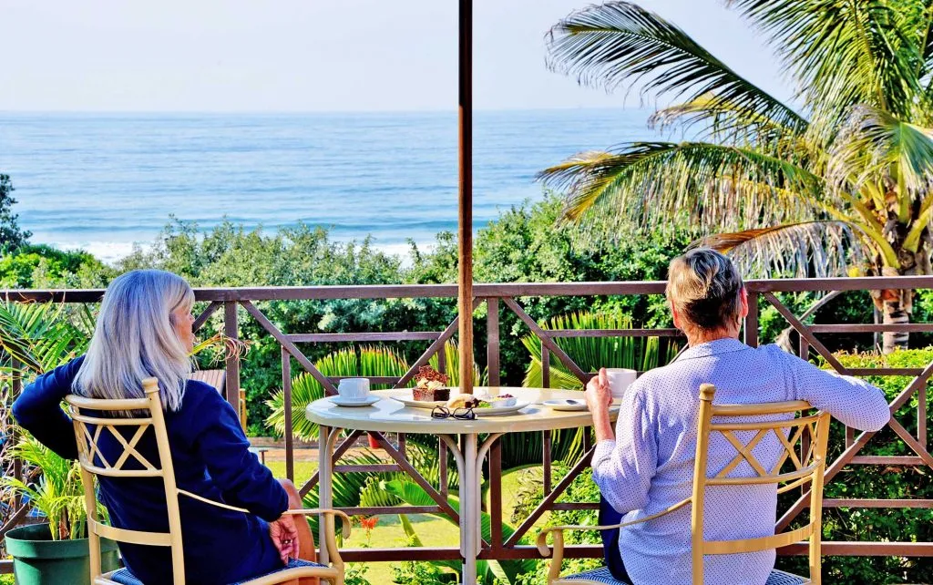 Two people sitting at a table with an ocean view and palm trees