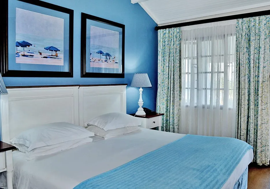 Blue bedroom with white bed beachthemed art and floral curtains