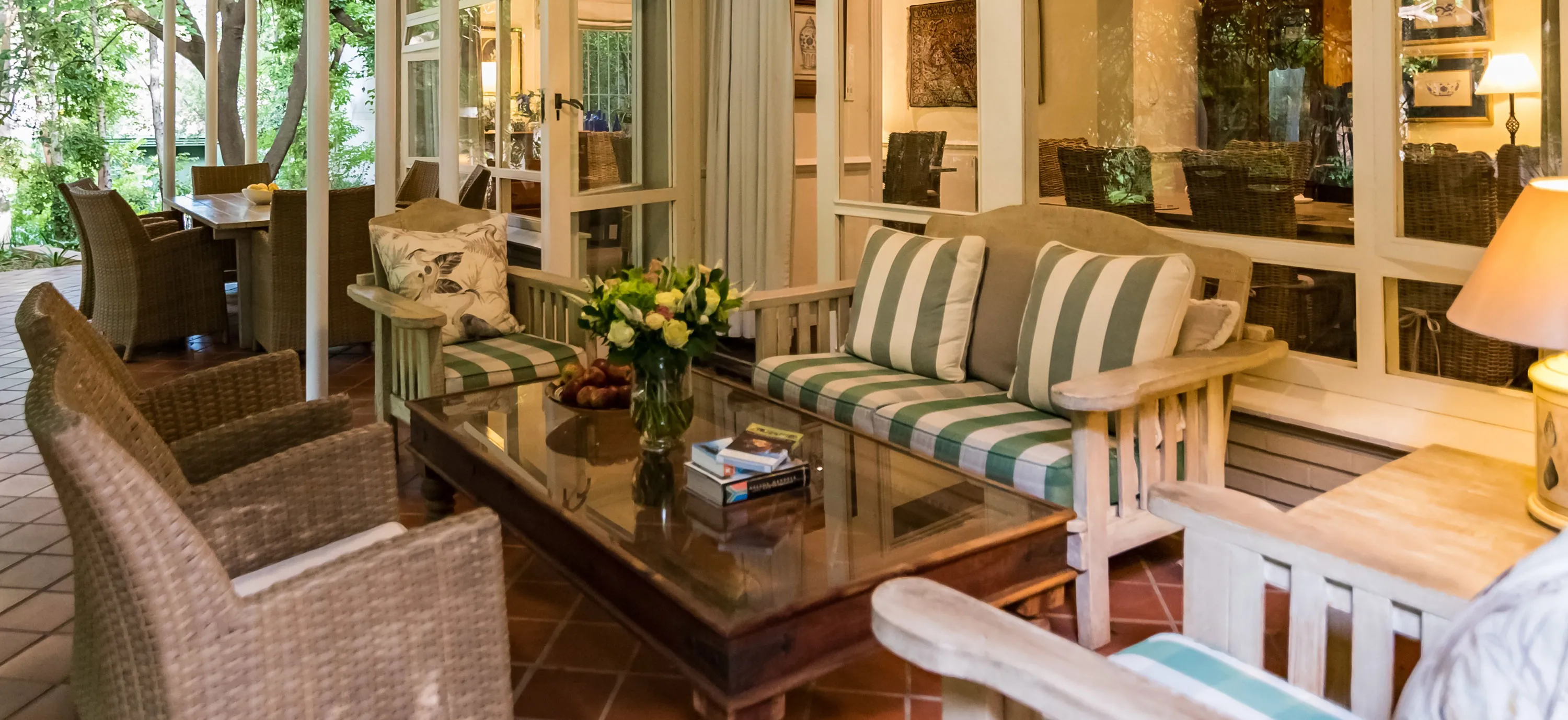 Sunlit patio with wicker furniture striped cushions and a glasstopped coffee table