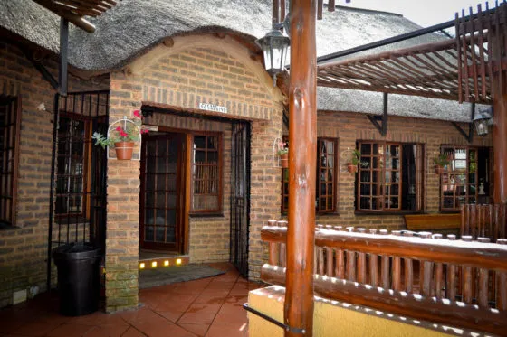 Thatchedroof building entrance with wooden door windows and potted flowers