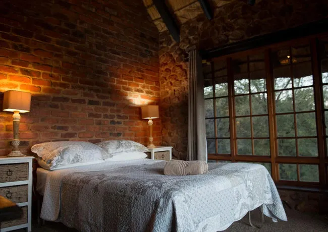 Cozy bedroom with a large bed brick wall and large windows