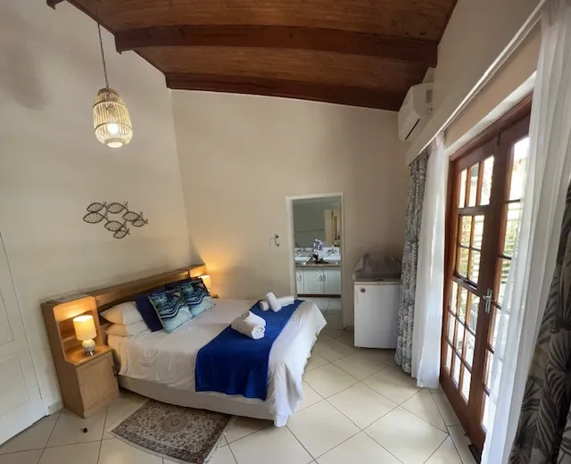 Cozy bedroom with wooden ceiling double bed and French doors to a patio