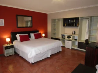 Modern bedroom with red walls white bedding and builtin shelves