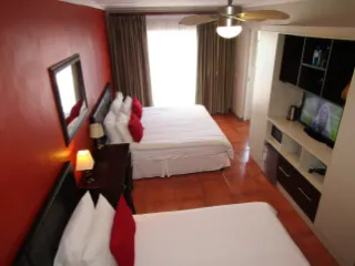 Two beds in a hotel room with red walls and a ceiling fan