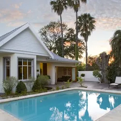 House with a swimming pool and palm trees at sunset
