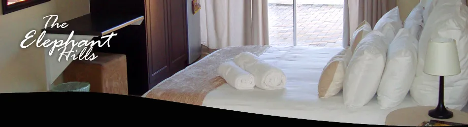 Hotel room with neatly made bed towels and The Elephant Hills text