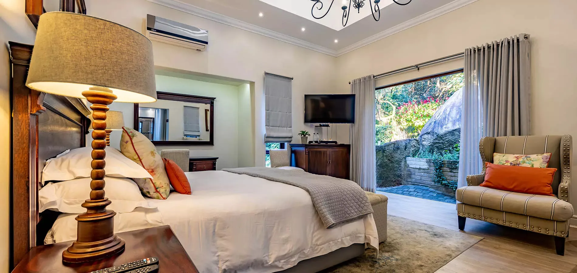 Cozy bedroom with large bed lamp armchair and open garden view