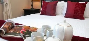 Breakfast tray on bed with tea set muffins and magazine in a bedroom