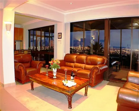 Leather living room furniture with city view through large windows at night