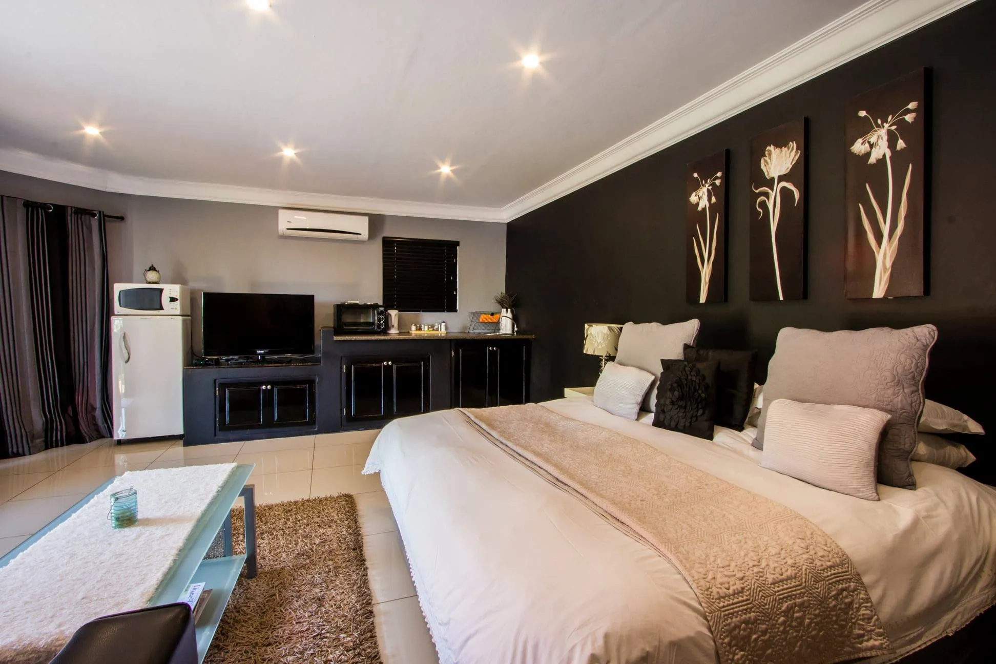 Modern bedroom with a large bed TV fridge and wall art