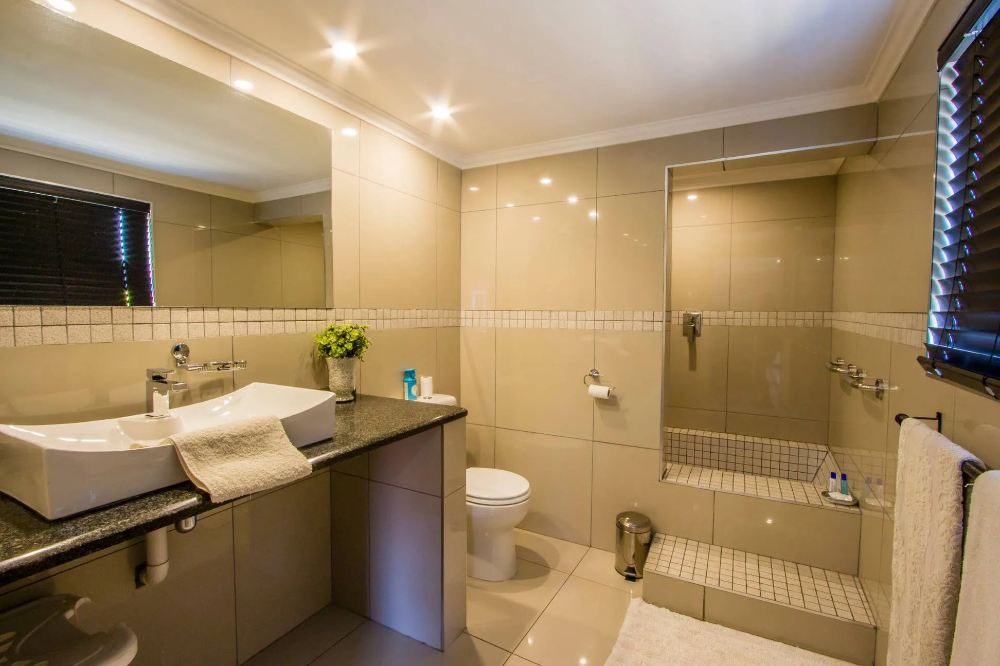 Modern bathroom with sink toilet and walkin shower featuring tiled walls and floor