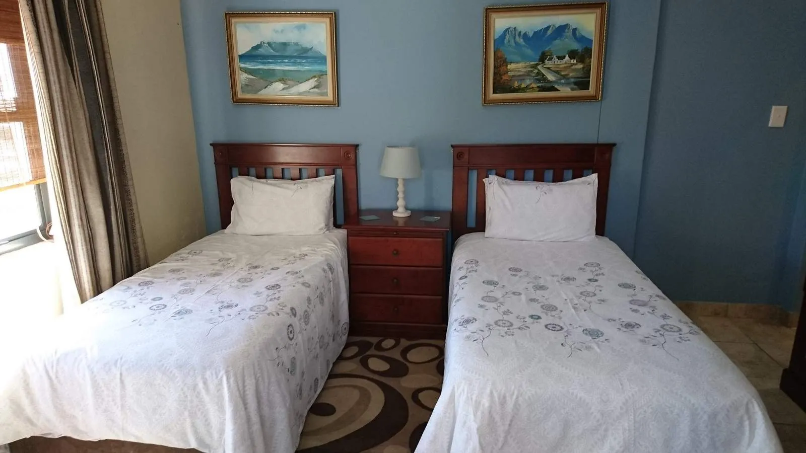 Two single beds in a tidy bedroom with blue and beige walls