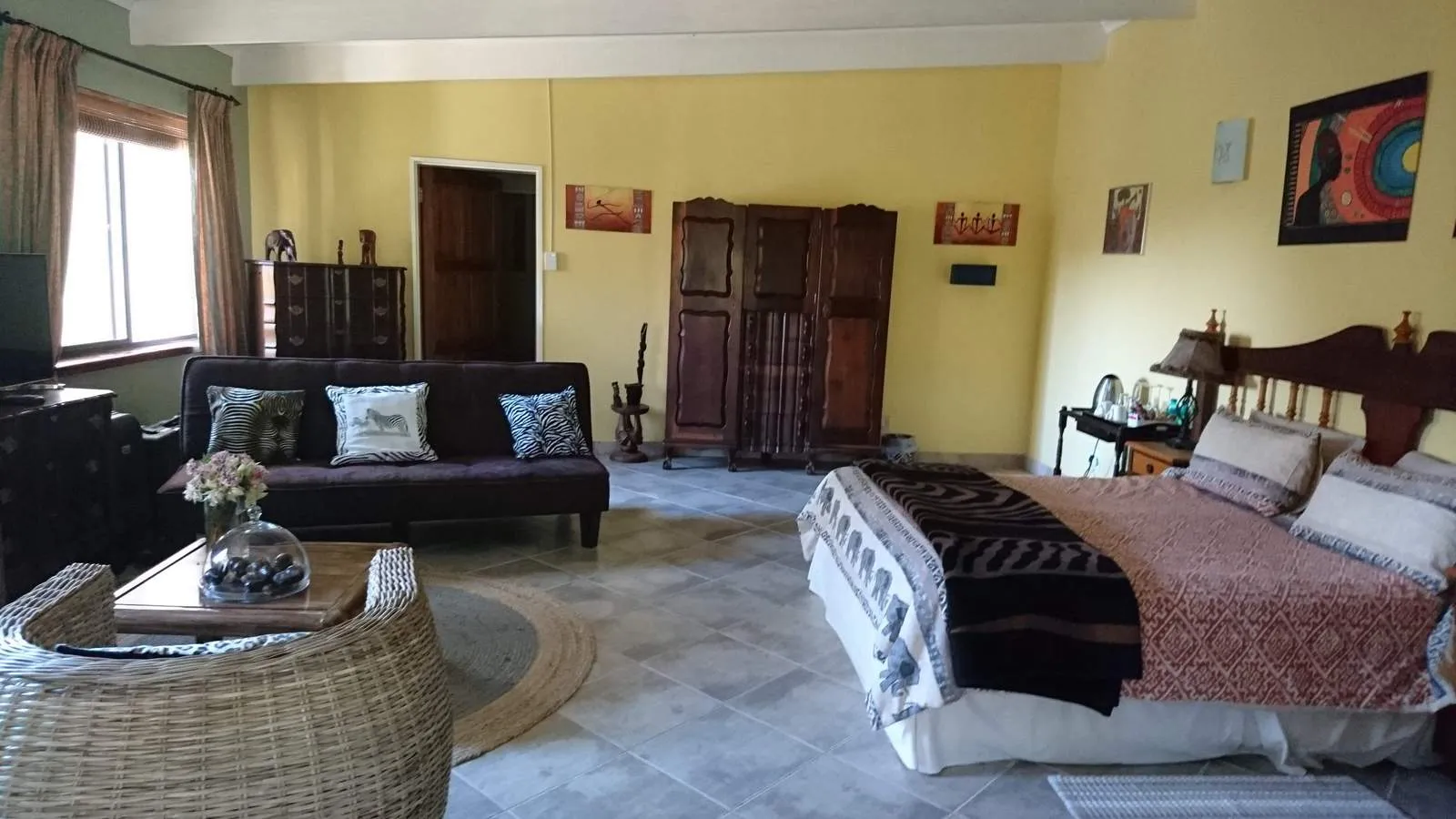Cozy bedroom with a bed sofa and wooden furniture yellow walls and artwork