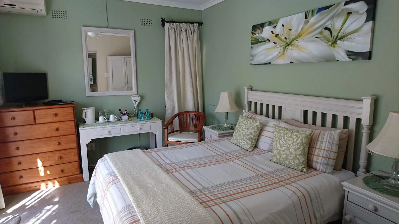 Cozy bedroom with a neatly made bed dresser and wall art