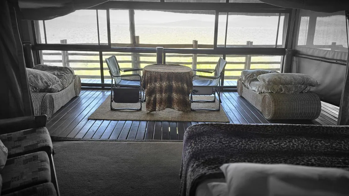 Bedroom with large window view table chairs and beds in a rustic setting