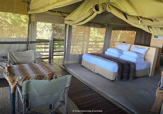 Luxury tent interior with a bed seating area and wooden deck