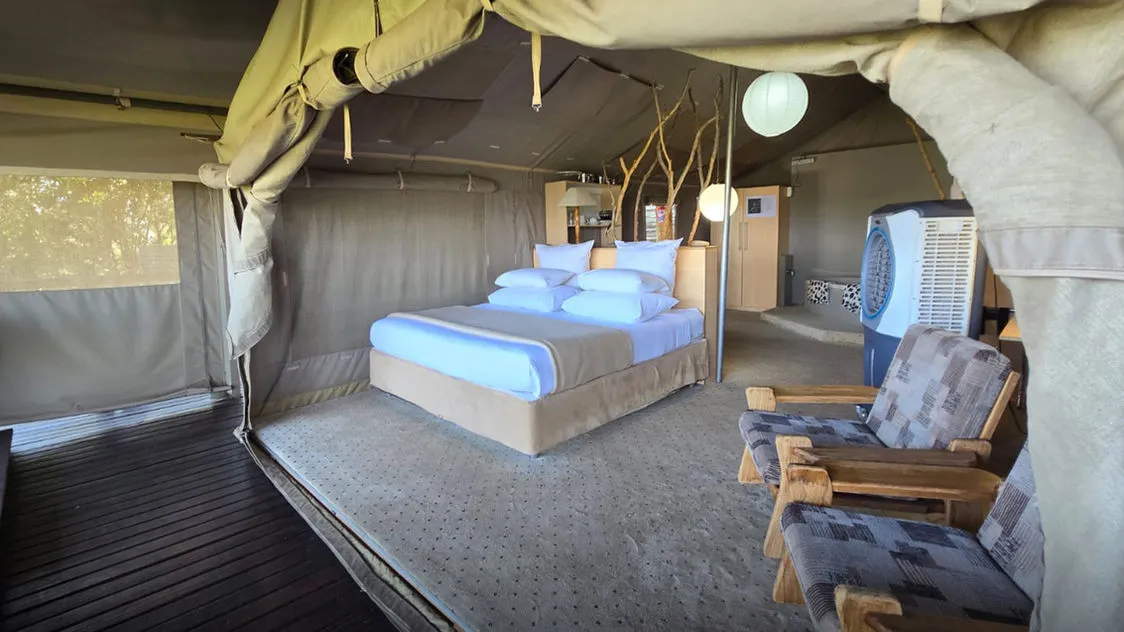 Luxury tent interior with bed chairs and air conditioner in a natural setting