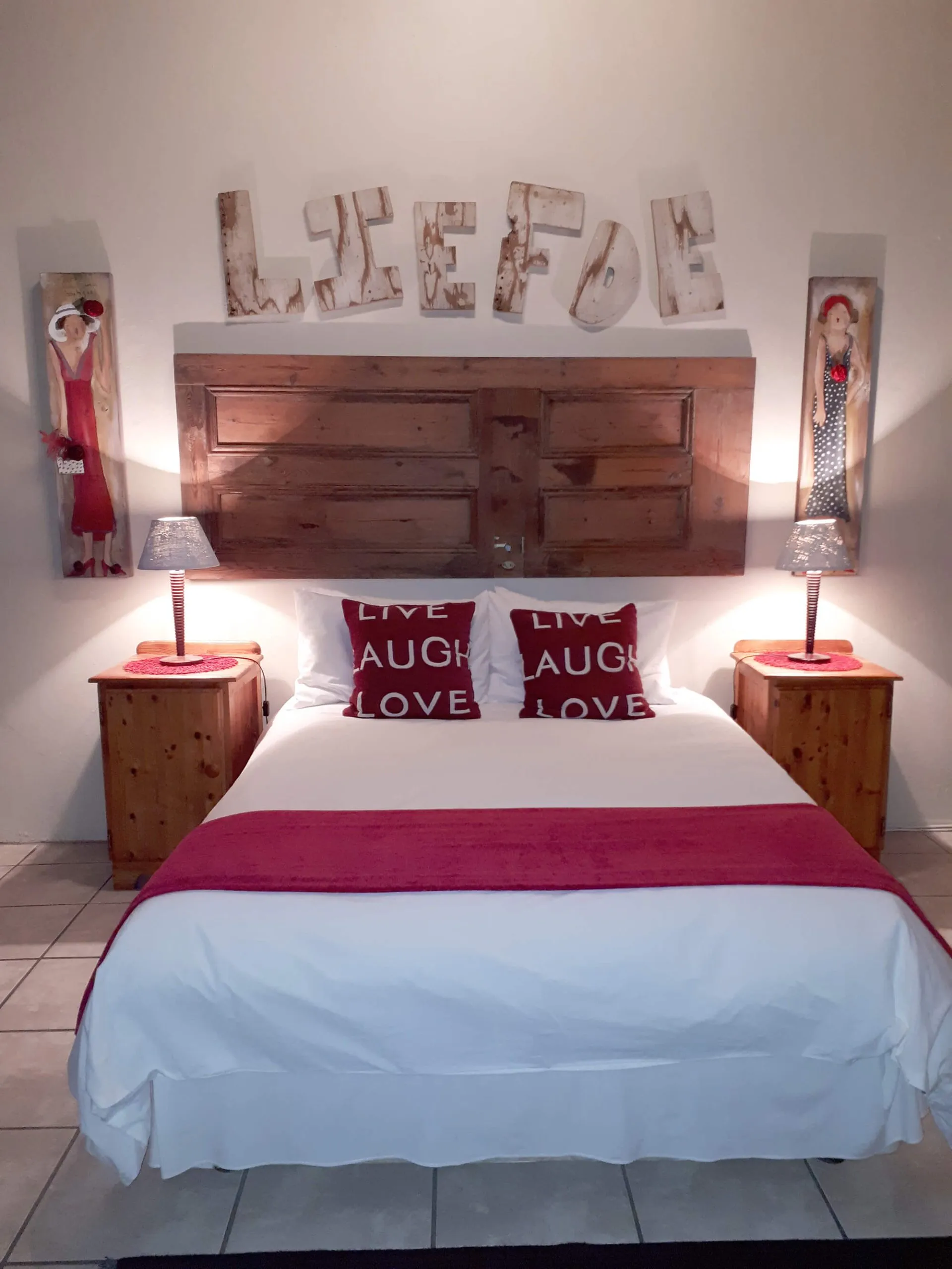 Wooden headboard with LIVE LOVE LAUGH pillows on a neatly made bed