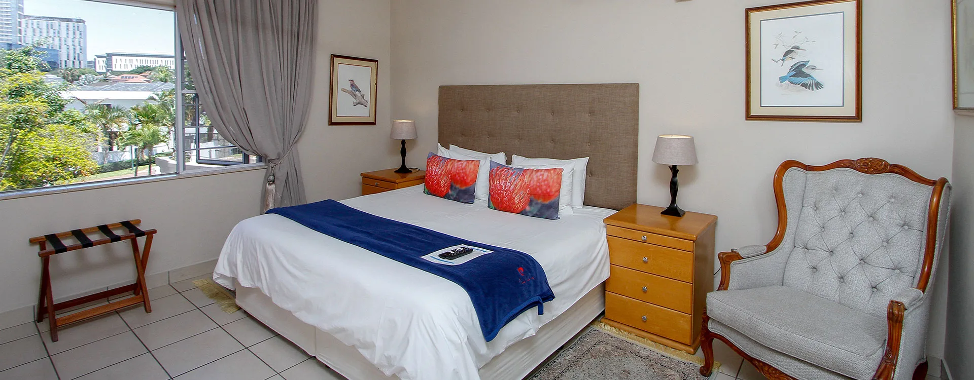 Bedroom with a large bed armchair and city view through a window