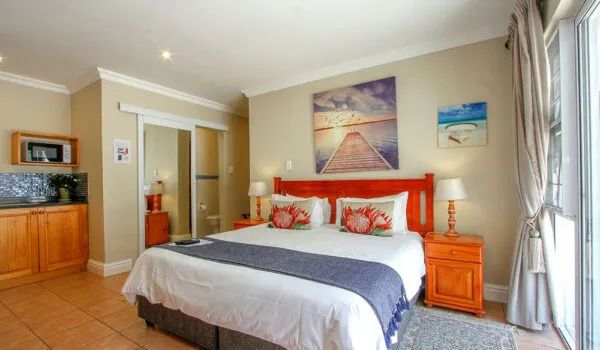 Cozy bedroom with a large bed wooden furniture and beachthemed artwork