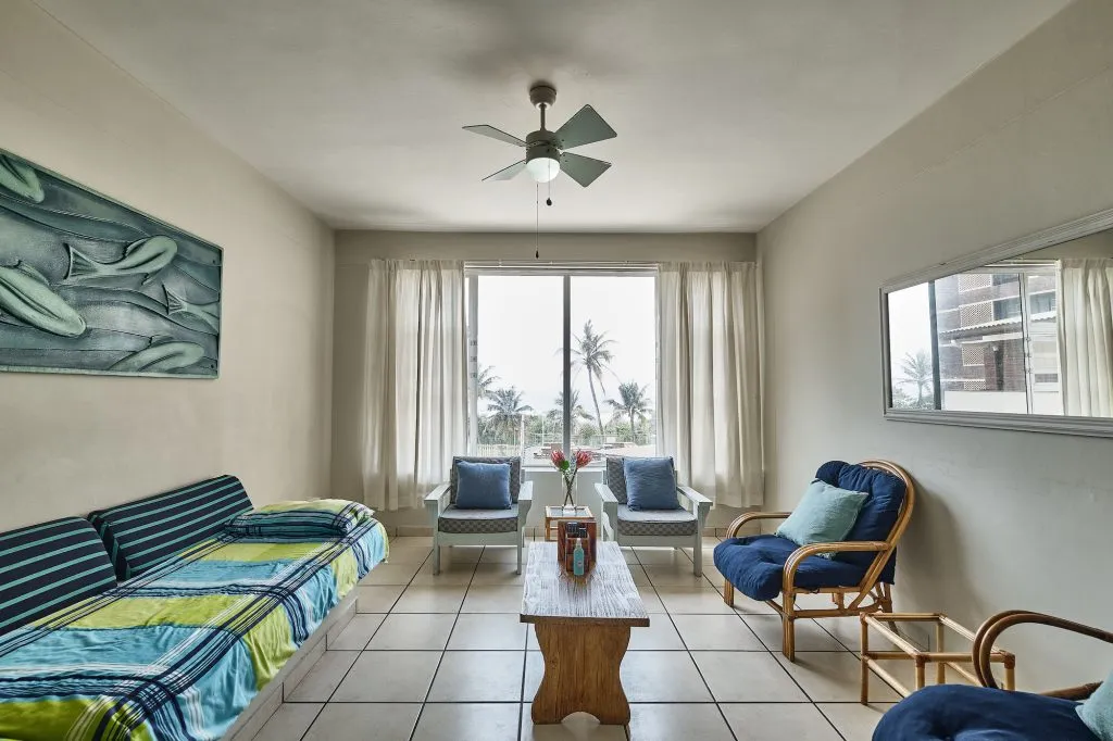 Living room with sofa chairs coffee table and large window with ocean view