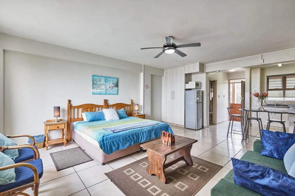 Bedroom with a bed sofa dining area and kitchenette in a studio apartment