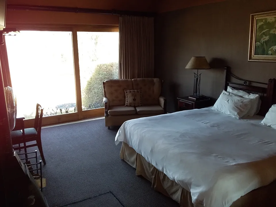 Hotel room with a bed sofa desk and large windows with curtains