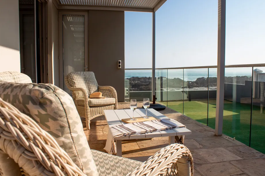 Wicker chairs on a patio with ocean view and stonetiled floor